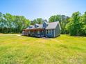 Charming blue home with a covered porch and mature trees, set on a sunny lot with green grass at 3546 Mount Pleasant N Rd, Concord, NC 28025