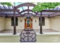 Charming covered front porch with wood beam pergola and a secure decorative metal gate at front at 455 W Gleneagles Rd, Statesville, NC 28625