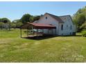 Backyard view of the home, featuring a carport and a spacious lawn at 4787 Rock Barn Rd, Claremont, NC 28610