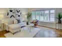 Bright living room with hardwood floors, modern decor, and a large bay window at 5601 Londonderry Rd, Charlotte, NC 28210