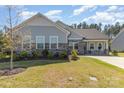 Inviting single-story home featuring stone accents, a manicured lawn, and a welcoming covered front porch with rocking chairs at 8011 Green Heron Ct, Belmont, NC 28012
