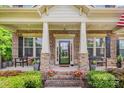 Charming brick front porch with decorative columns, stylish seating, and flower planters at 8169 Clems Branch Rd, Indian Land, SC 29707