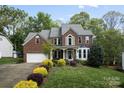 Charming two-story brick home with lush landscaping, mature trees, and attached two-car garage at 9009 Tayside Ct, Huntersville, NC 28078