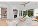 Bright living room with a white fireplace, modern ceiling fan, hardwood floors, and large windows with greenery views at 9020 Tynecastle Commons Ct, Charlotte, NC 28226