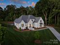 Expansive aerial view showcasing pristine landscaping, modern white brick home, and a serene wooded backdrop at 100 Verbena Ct, Weddington, NC 28173
