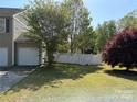 Backyard featuring a well maintained lawn, enclosed by a white fence, and lush trees at 1104 Valley St, Statesville, NC 28677