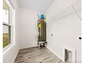 Bright utility room featuring a window, water heater, shelving, and wood-look flooring at 1301 Marble St, Charlotte, NC 28208
