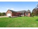 Charming brick home featuring manicured lawn, attached two-car garage, and welcoming front porch on a sunny day at 131 Fieldhaven Pl, Troutman, NC 28166