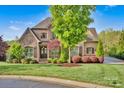 Beautiful home featuring a blend of stone and brick, accented by lush greenery and mature trees at 17909 Golden Meadow Ct, Davidson, NC 28036
