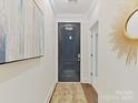 Inviting foyer with a dark door, stylish rug, modern light fixture and gleaming wood floors at 3064 Selwyn Ave, Charlotte, NC 28209