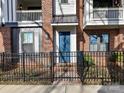 Charming townhouse entrance featuring a vibrant blue door, wrought iron fence, and brick accents at 3064 Selwyn Ave, Charlotte, NC 28209