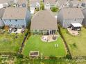 Aerial backyard view featuring a patio area with a fire pit, manicured lawn, and a fence-enclosed outdoor space at 3129 Burnello Ct, Iron Station, NC 28080