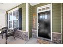 Cozy front porch featuring a stylish black door, stacked stone accents, and comfortable seating for relaxing outdoors at 3129 Burnello Ct, Iron Station, NC 28080