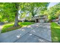 Suburban home with a lush green lawn, mature trees, and a long driveway leading to the garage at 4224 Firwood Ln, Charlotte, NC 28209