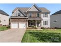 Charming two-story home featuring a stone facade, covered porch, and well-manicured lawn at 5035 Terrier Ln, Fort Mill, SC 29707