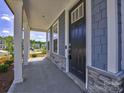 Covered front porch showcasing stone accents, a black front door, and sturdy white columns adding to the home's curb appeal at 6114 Alsace Ln, Indian Land, SC 29707