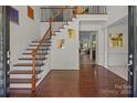 Open foyer with hardwood floors, staircase with iron railings, and view into other living spaces at 9494 Leyton Dr, Harrisburg, NC 28075