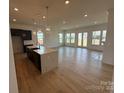 Open-concept kitchen and living room with hardwood flooring, many windows and a kitchen island at 13279 Arnold Palmer Cir # 867, Lancaster, SC 29720