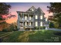 Elegant home with a double porch, stone facade, and inviting curb appeal at twilight at 14010 Promenade Dr, Huntersville, NC 28078