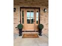 Close-up of an elegant front door with glass panes, flanked by topiary and a welcome mat at 15906 Youngblood Rd, Charlotte, NC 28278