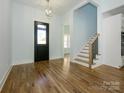 Bright foyer featuring hardwood floors, a staircase with black iron balusters, and modern lighting at 2008 Plain Field Dr, Bessemer City, NC 28016