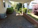 Gravel driveway with brick retaining wall and lush greenery, offering a private outdoor space at 202 S Love Chapel Rd, Stanfield, NC 28163