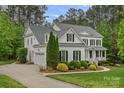 Side view of a white two-story home with an attached garage, complemented by lush landscaping at 208 Grasshopper Cir, Mooresville, NC 28117
