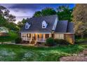 Charming brick home with a covered front porch and manicured lawn at dusk at 308 Valhalla Dr, Harrisburg, NC 28075
