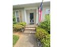 Inviting front entrance with brick steps, complemented by vibrant landscaping and an American flag at 317 Robert Keever Rd, Stanley, NC 28164
