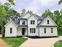 Beautiful two-story home with white siding, black accents, a well manicured lawn, and a concrete driveway at 3308 Watkins Rd, Monroe, NC 28110