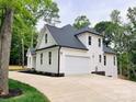 View of the side exterior elevation with a white garage door and white siding against a well manicured lawn at 3308 Watkins Rd, Monroe, NC 28110