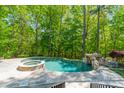 Beautiful backyard pool with waterfall feature, hot tub, and stone pavers at 5868 Savona Ter, Fort Mill, SC 29708