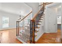 Elegant staircase with hardwood steps, carpet runner, and decorative iron railing, adding architectural interest to the home at 6201 Creola Rd, Charlotte, NC 28270