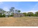 Spacious lot with a quaint house featuring a covered porch, set against a backdrop of mature trees and blue sky at 6525 Kershaw Camden Hwy, Heath Springs, SC 29058