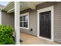 Close-up of the front door with decorative trim, a window, and manicured landscaping at 13012 Hunting Birds Ln, Charlotte, NC 28278