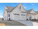 Elegant home featuring a three-car garage, white siding, and black accents against a clear blue sky at 13097 Arnold Palmer Cir # 844, Lancaster, SC 29720