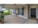 Covered front porch featuring black door, symmetrical shuttered windows, and ample seating space at 13103 Union Square Dr, Huntersville, NC 28078