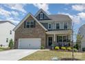 Two-story home with brick and gray siding, attached garage, and manicured lawn, under a blue sky with clouds at 17231 Rider Wood Ln, Charlotte, NC 28278