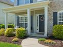 Welcoming covered porch with decorative wreath, stylish seating, and colorful flower beds at 2002 Potomac Rd, Indian Trail, NC 28079