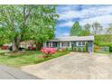 Inviting single-story home with a spacious driveway, mature trees, and colorful azalea bushes at 400 Rhyne St, Stanley, NC 28164