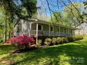 Side view of a charming home with a welcoming front porch, surrounded by beautiful greenery and flowering bushes at 531 Hattaway Dr, Mount Gilead, NC 27306