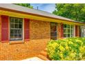 Close up on the brick facade, red shutters, and manicured greenery of this charming home at 862 Eastwood Dr, Rock Hill, SC 29730