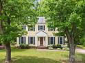 Charming yellow two-story home with blue shutters, lush front lawn, and mature shade trees at 1007 Doby Springs Dr, Charlotte, NC 28262