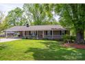 Inviting brick home featuring a quaint, covered porch and lush front lawn with mature trees at 111 Peoria Ln, Kings Mountain, NC 28086