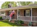 Inviting front porch with brick facade, white railing, and a welcoming American flag at 111 Peoria Ln, Kings Mountain, NC 28086