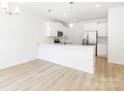 Bright, open-concept kitchen featuring white cabinets, a breakfast bar, stainless steel appliances, and hardwood floors at 1141 Thayer Glen Ct, Charlotte, NC 28213
