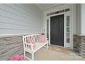Charming front door with white bench, colorful pillows, and decorative stonework at 13115 Union Square Dr, Huntersville, NC 28078