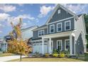 View of the gray two-story house with white trim, and a manicured front lawn and landscaped flower beds at 1390 Cedardale Ln, Denver, NC 28037