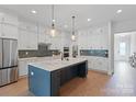 Modern kitchen featuring white cabinets, stainless steel appliances, a spacious island, and stylish pendant lighting at 1390 Cedardale Ln, Denver, NC 28037