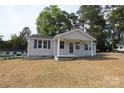 Well-maintained single-story house with a welcoming porch, light siding, and dark shutters in a serene setting at 306 E Burnsville St, Wadesboro, NC 28170